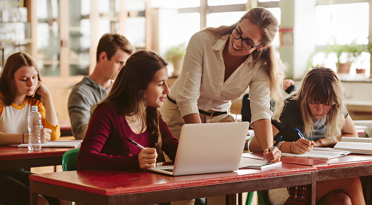 Teacher assisting students in a classroom.