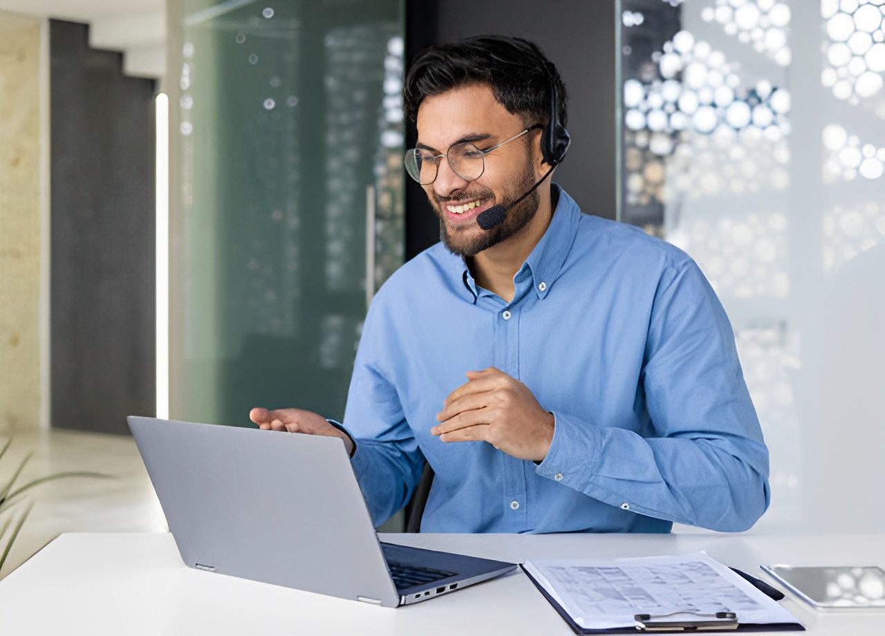 Man using laptop and headset in office.
