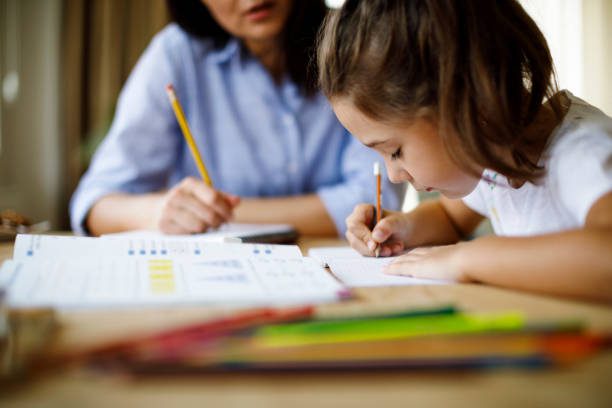 Child writing with adult's guidance at table.